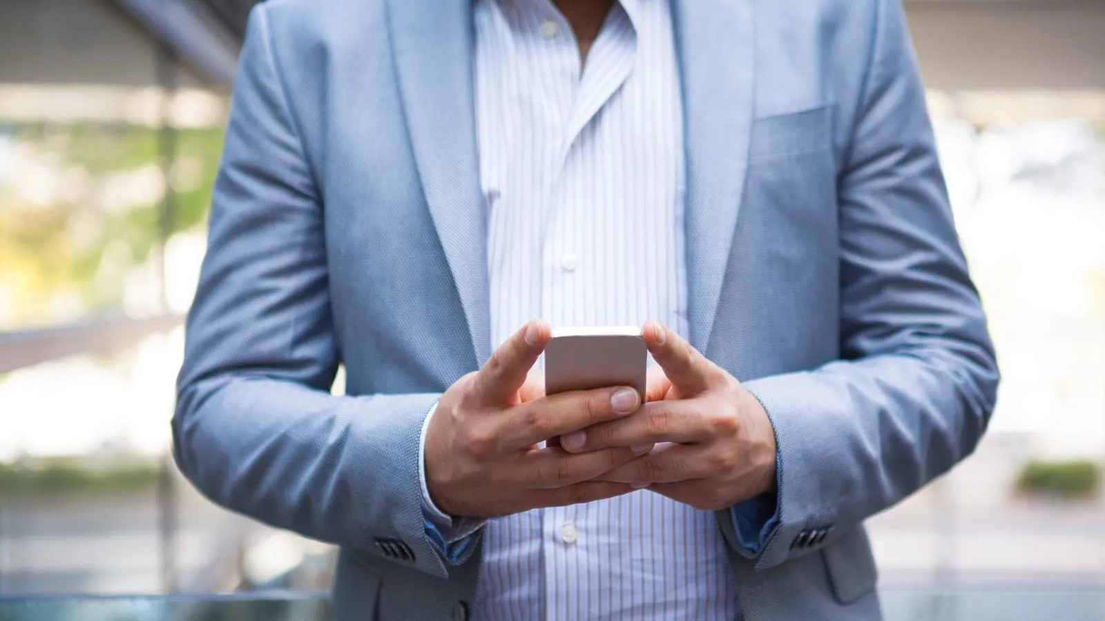 Mãos de um vendedor digitando uma mensagem no celular