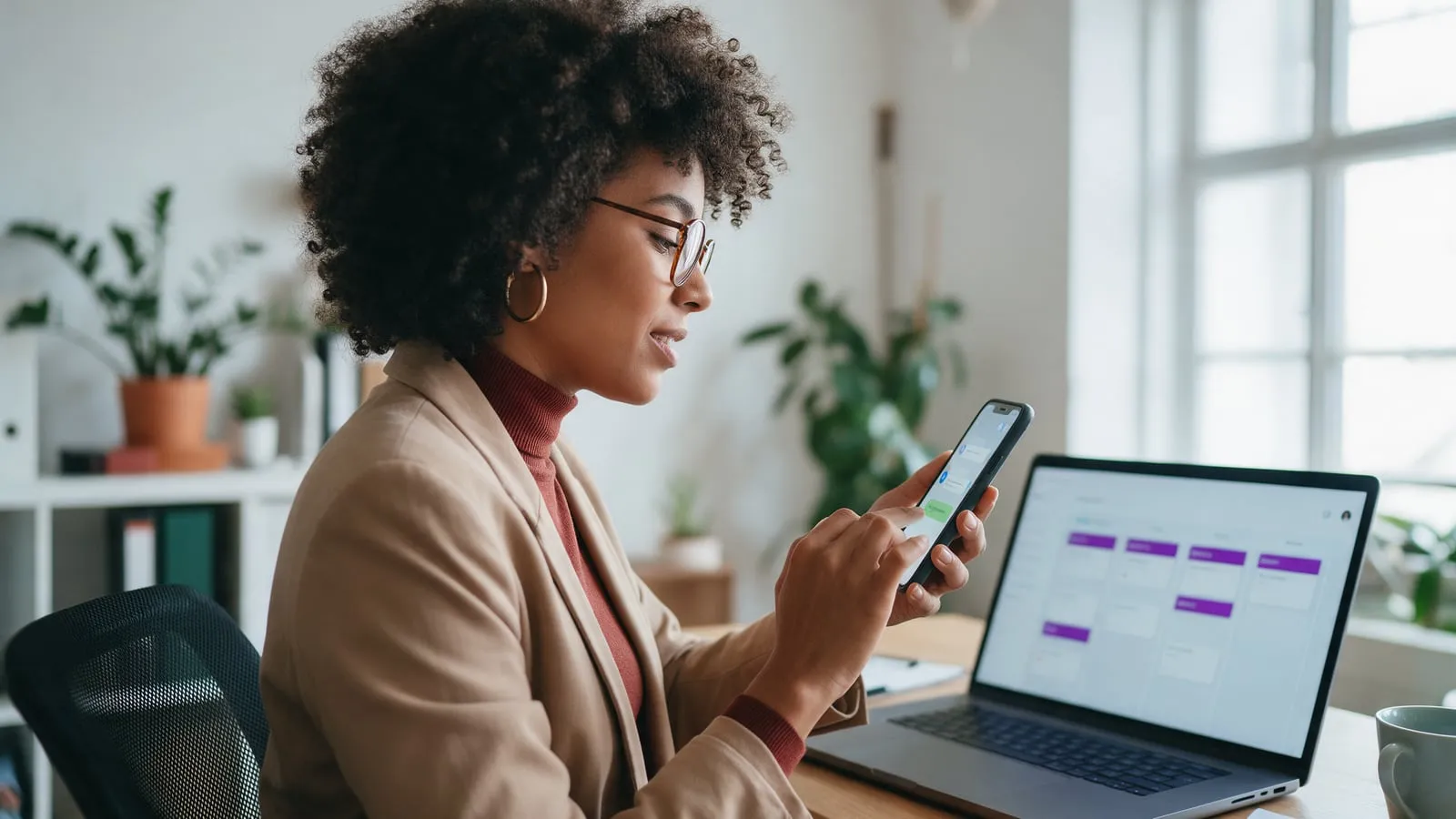 Vendedora responde um novo contato pelo celular com o CRM aberto no notebook, reduzindo o custo de aquisição de cliente